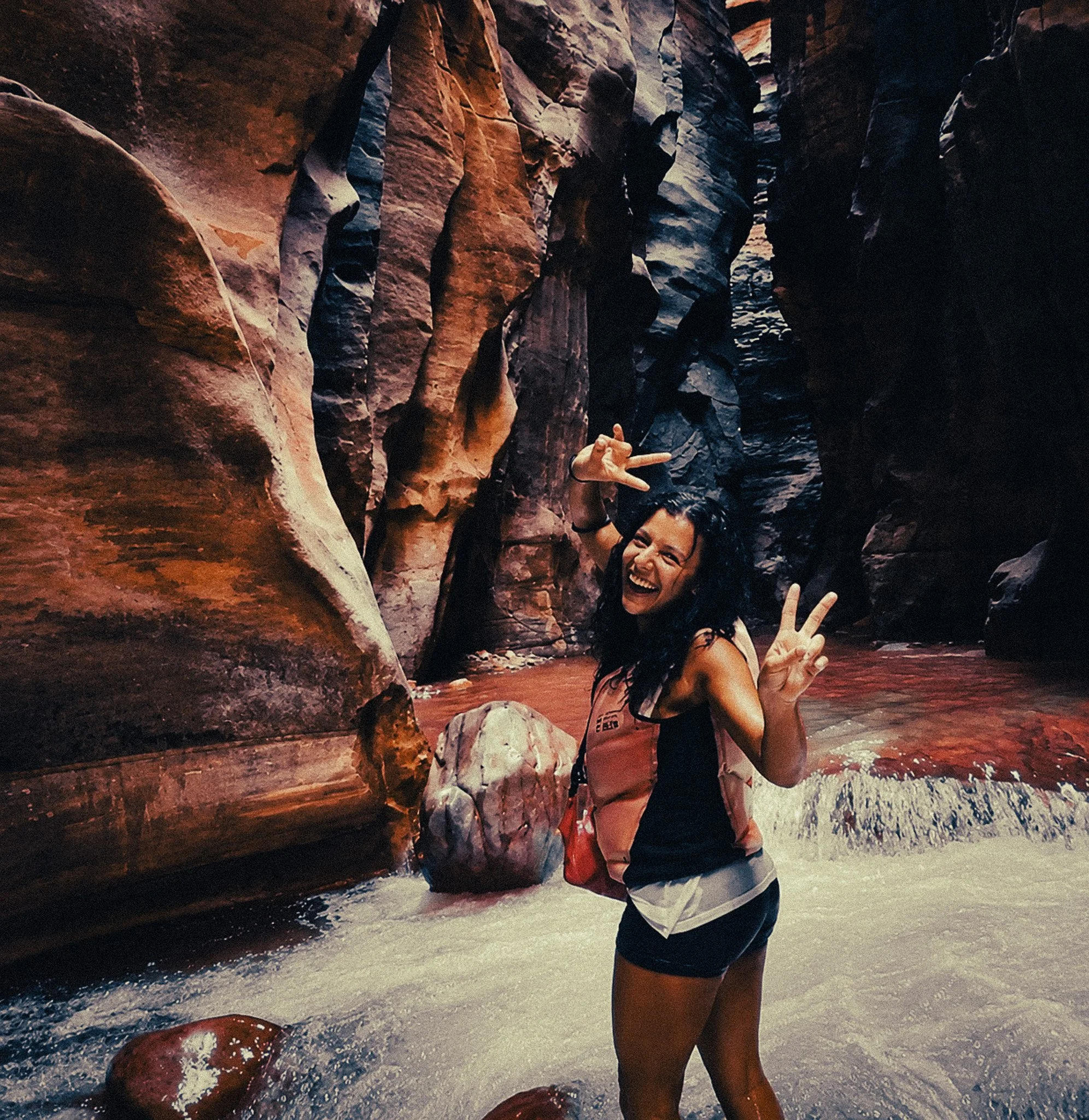 Woman smiling doing a sign of piece inside the canyons in wadi mujib jordan
