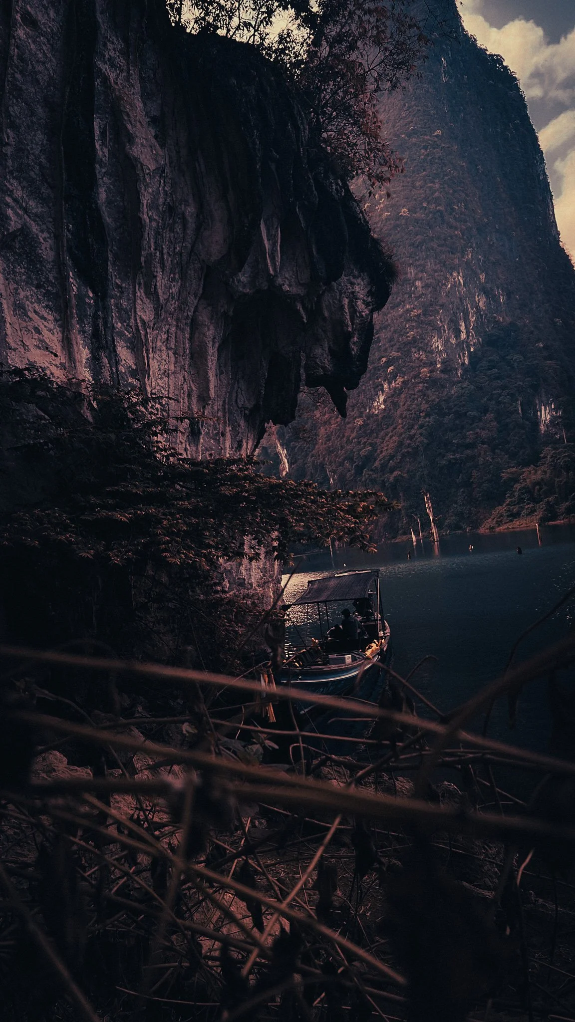 Longtail boat beneath towering limestone cliffs on Cheow Lan Lake, Khao Sok National Park.