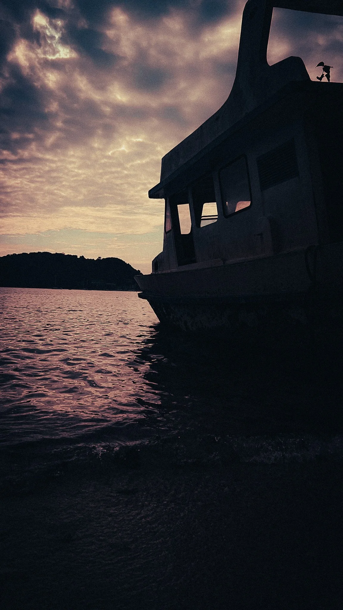 Boat silhouetted against the evening sky on the coast of Phuket, Thailand.