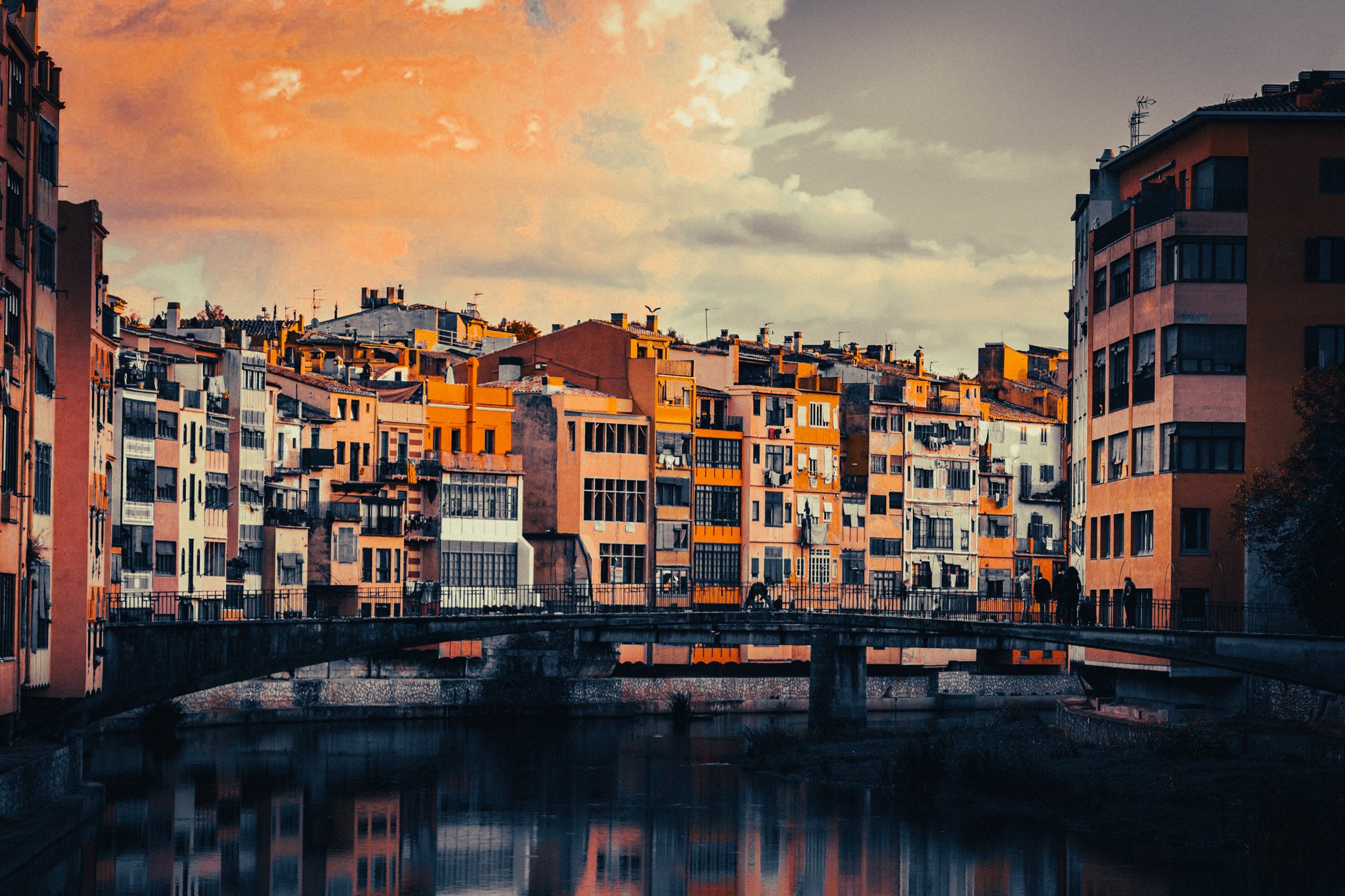 Girona old town houses along the river with a bridge in the foreground, one of the best day trips from Barcelona by train.