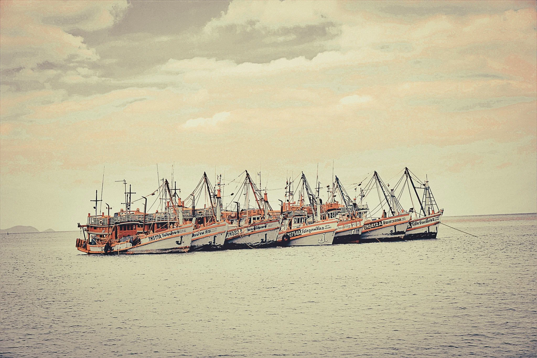 Traditional Thai fishing boats lined up together on the sea near Phuket.
