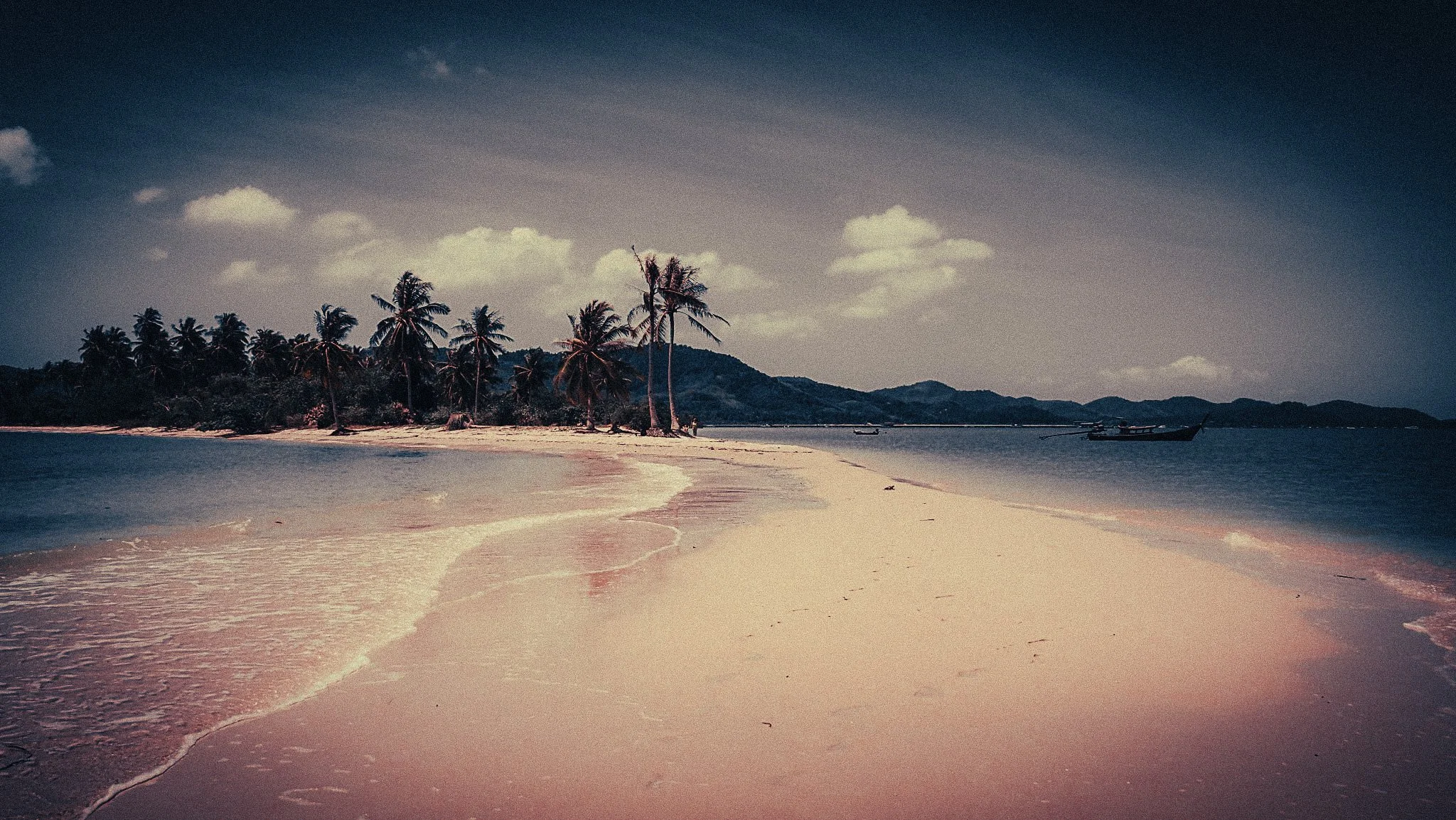 Empty sandbar and palm-lined beach in Koh Yao Yai, Thailand, with fishing boats offshore.