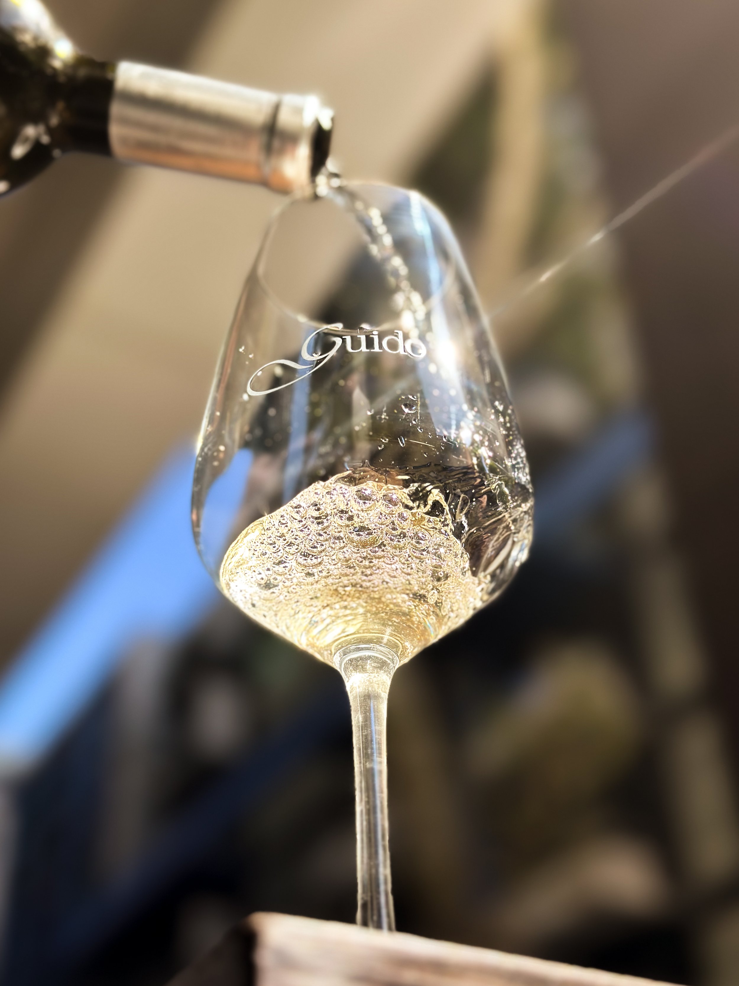 A glass of champagne being poured from a bottle with bubbles forming inside the glass.