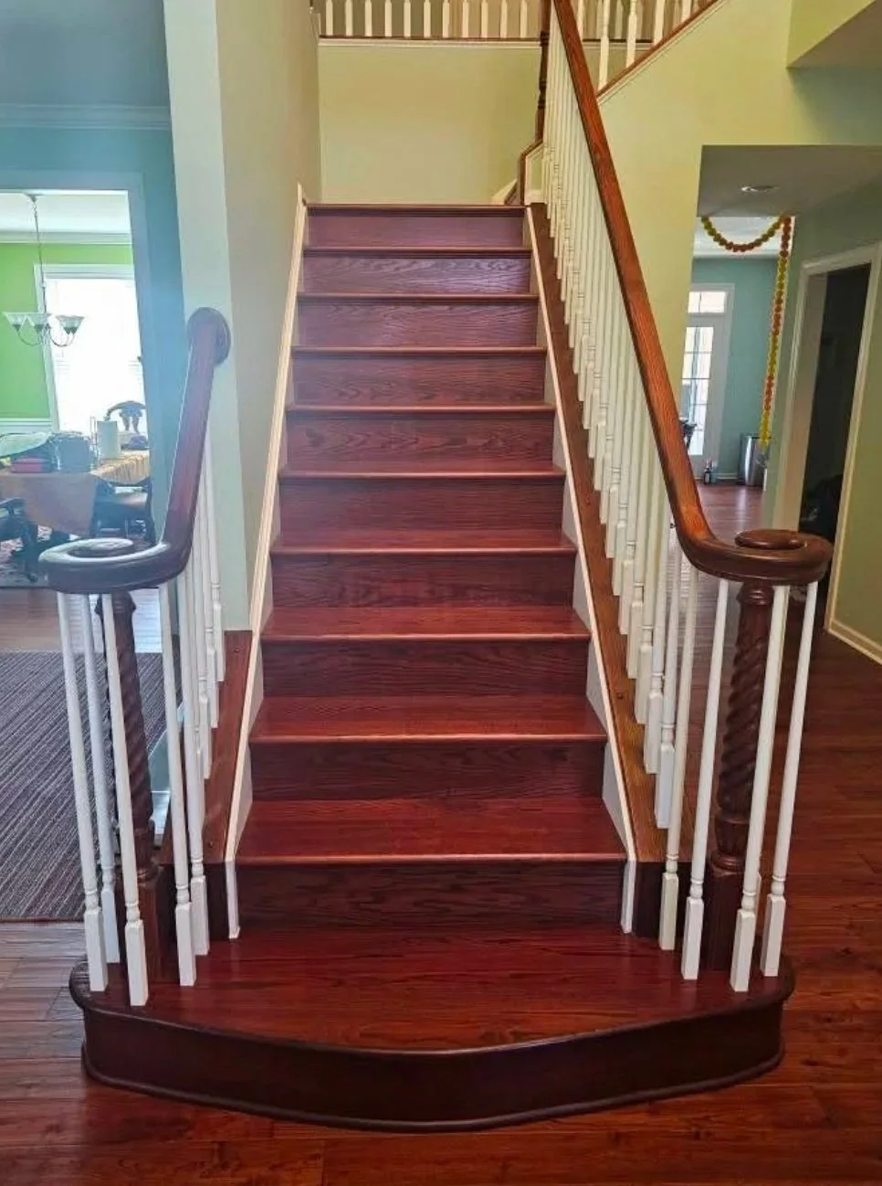 Wood staircase with dark brown steps, white spindles, and a wooden handrail leading to an upper floor, located in a home interior.