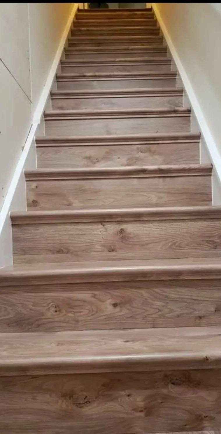 Wooden staircase with beige walls on either side.