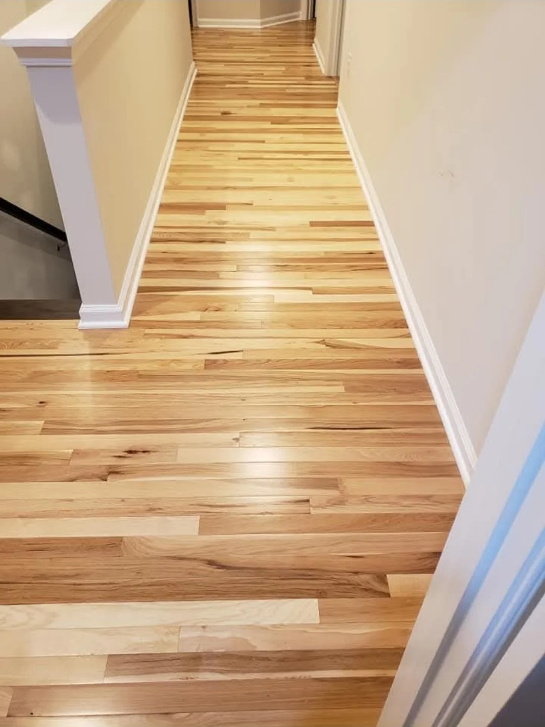 Polished hardwood floor hallway with cream-colored walls and white baseboards.
