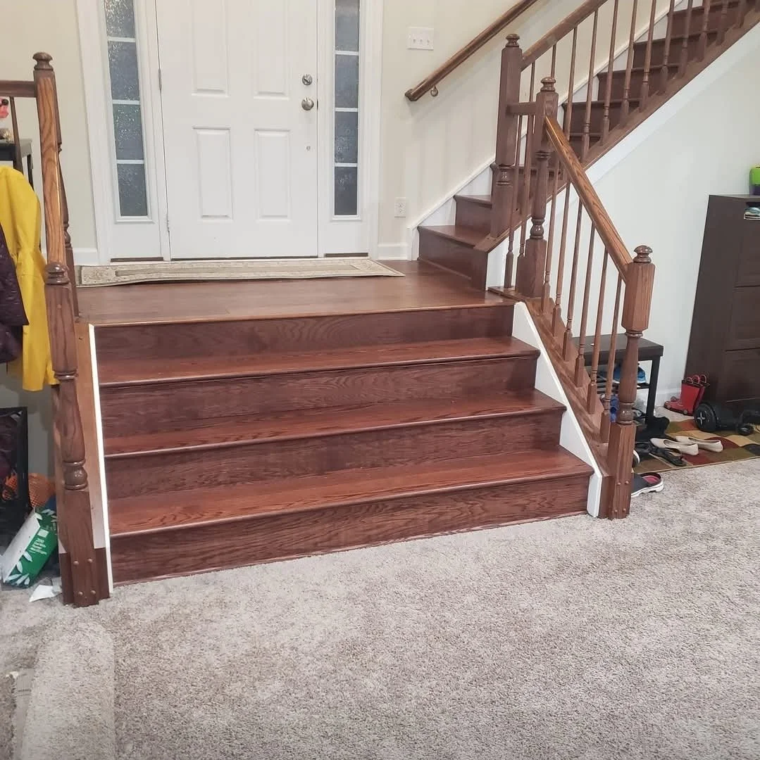 Wooden interior staircase leading to a white front door with glass panels on each side.