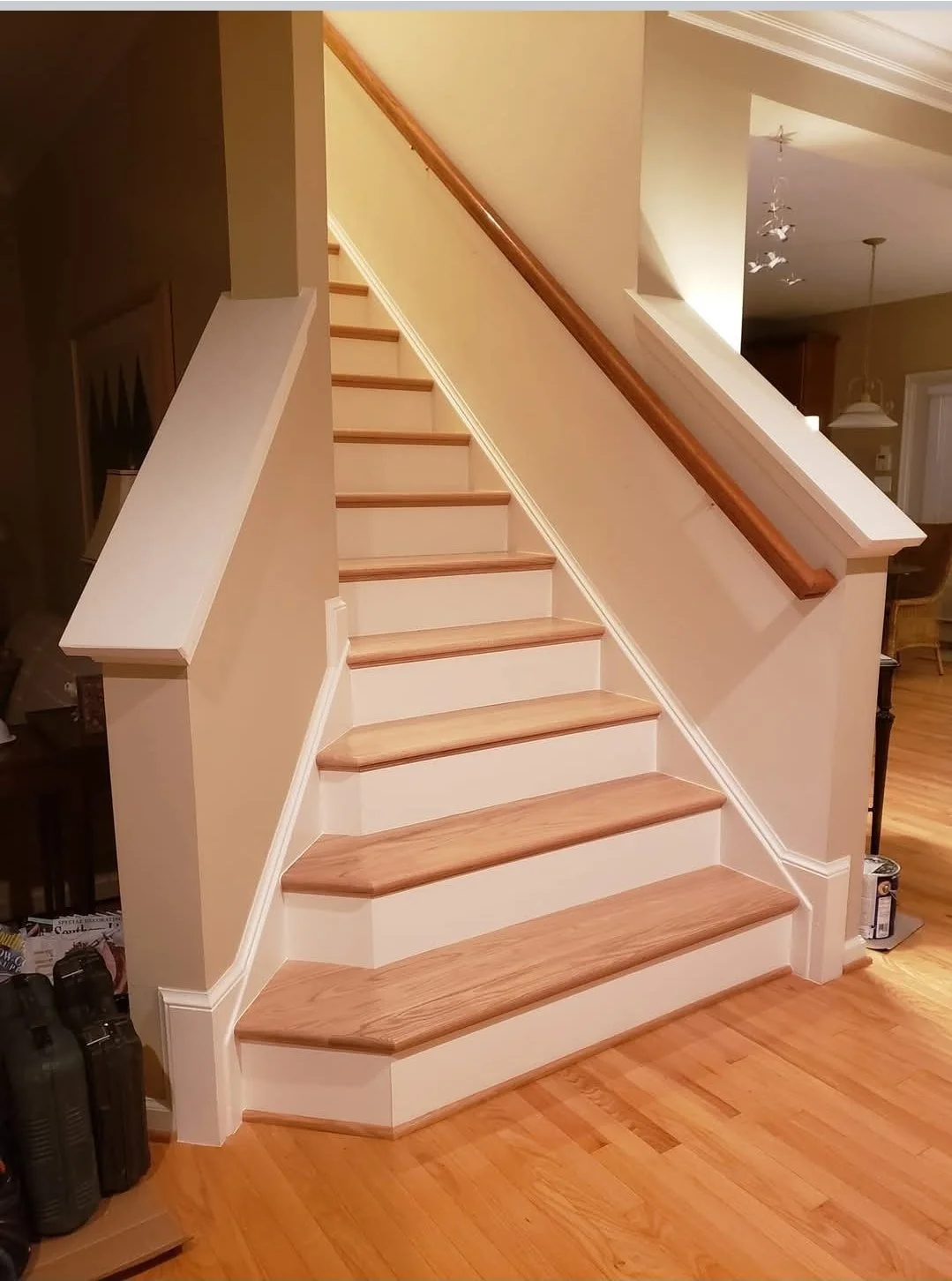 Wooden staircase with a railing on the right side, leading upstairs in a home interior, with hardwood flooring and warm lighting.