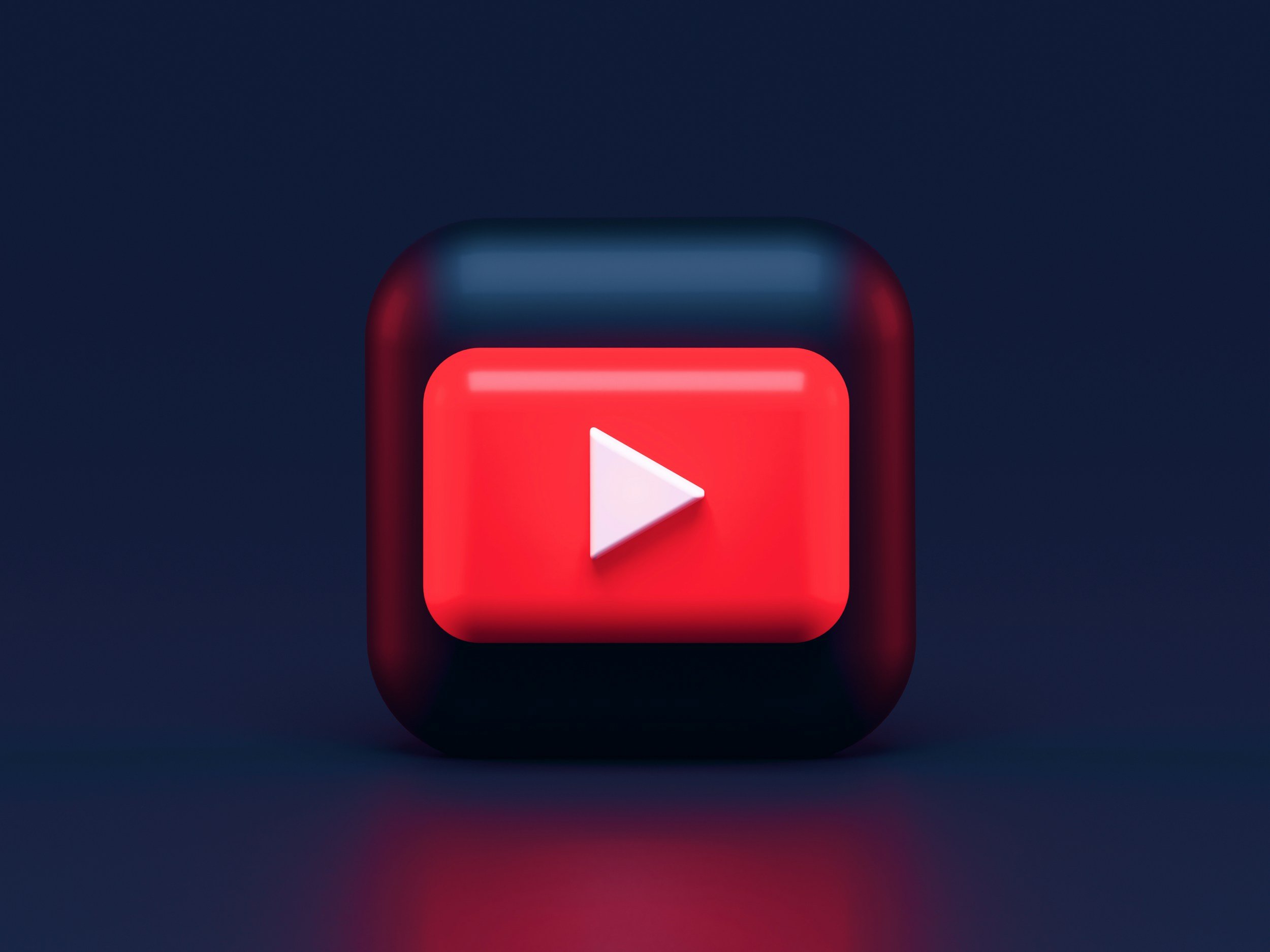 3D illustration of a black square app icon with rounded edges, featuring a red play button centered on it, representing YouTube logo, set against a dark background.