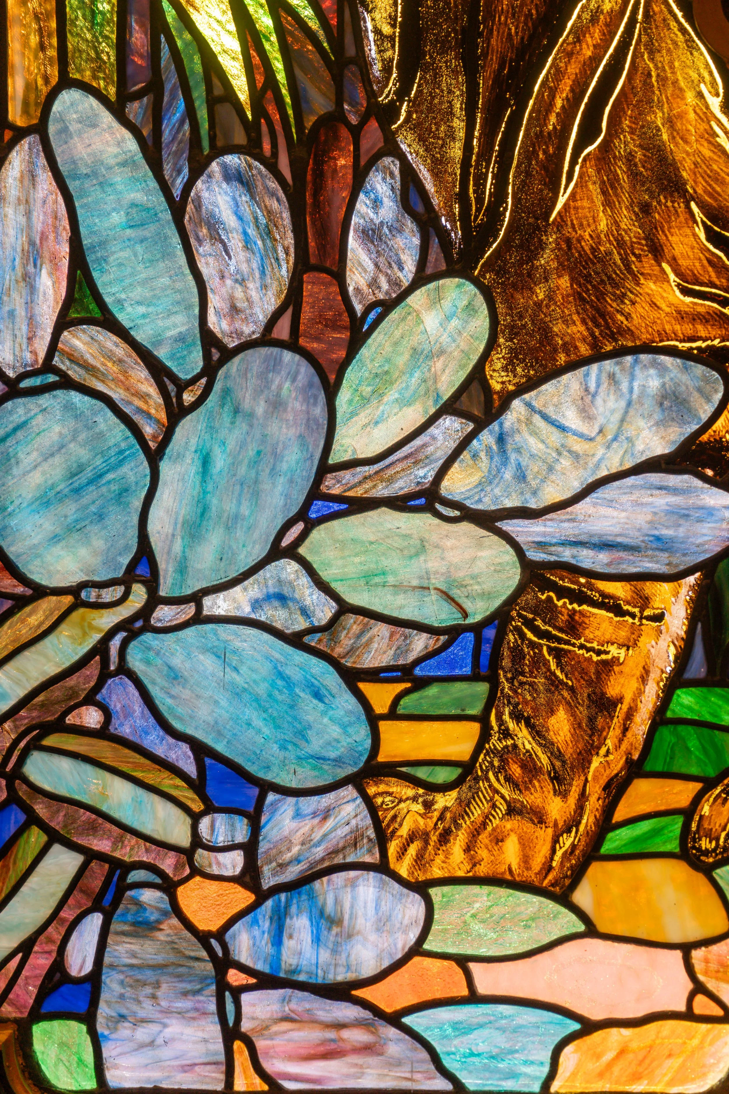 Colorful stained glass window with abstract floral patterns and vibrant hues of blue, green, yellow, orange, and red.