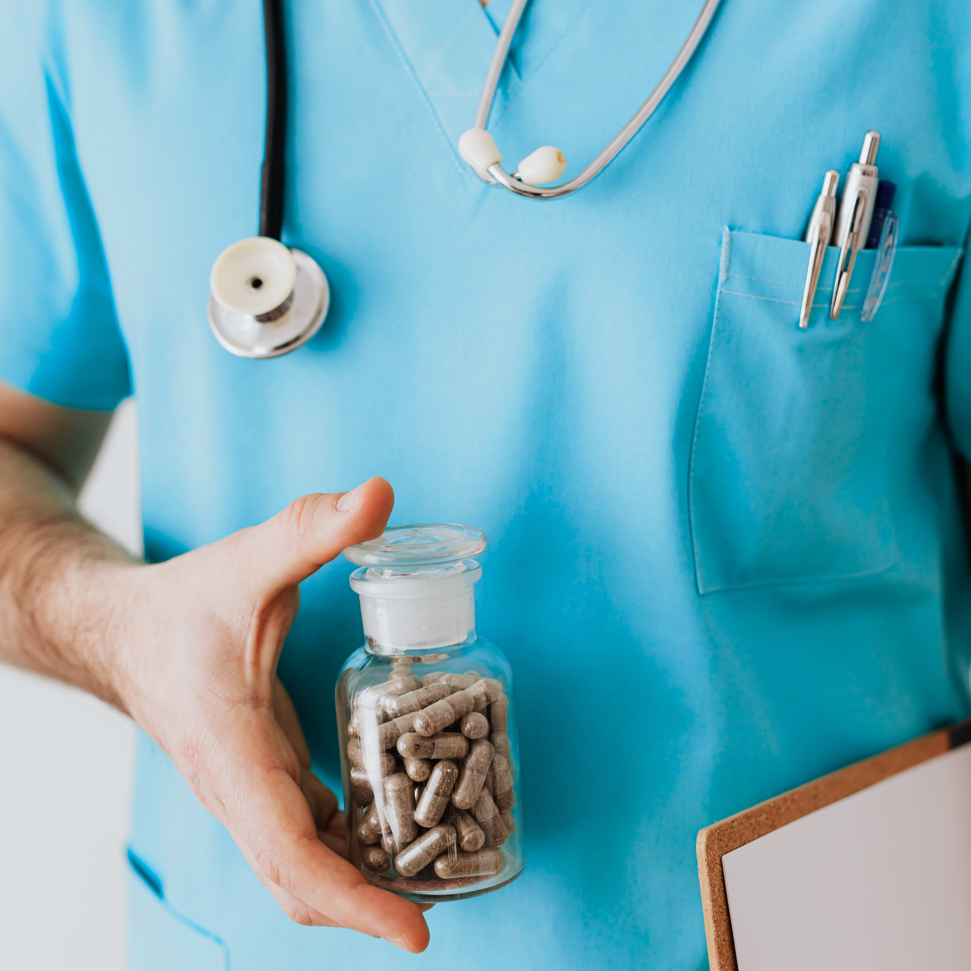 Close-up of a healthcare professional holding a glass jar filled with medication.