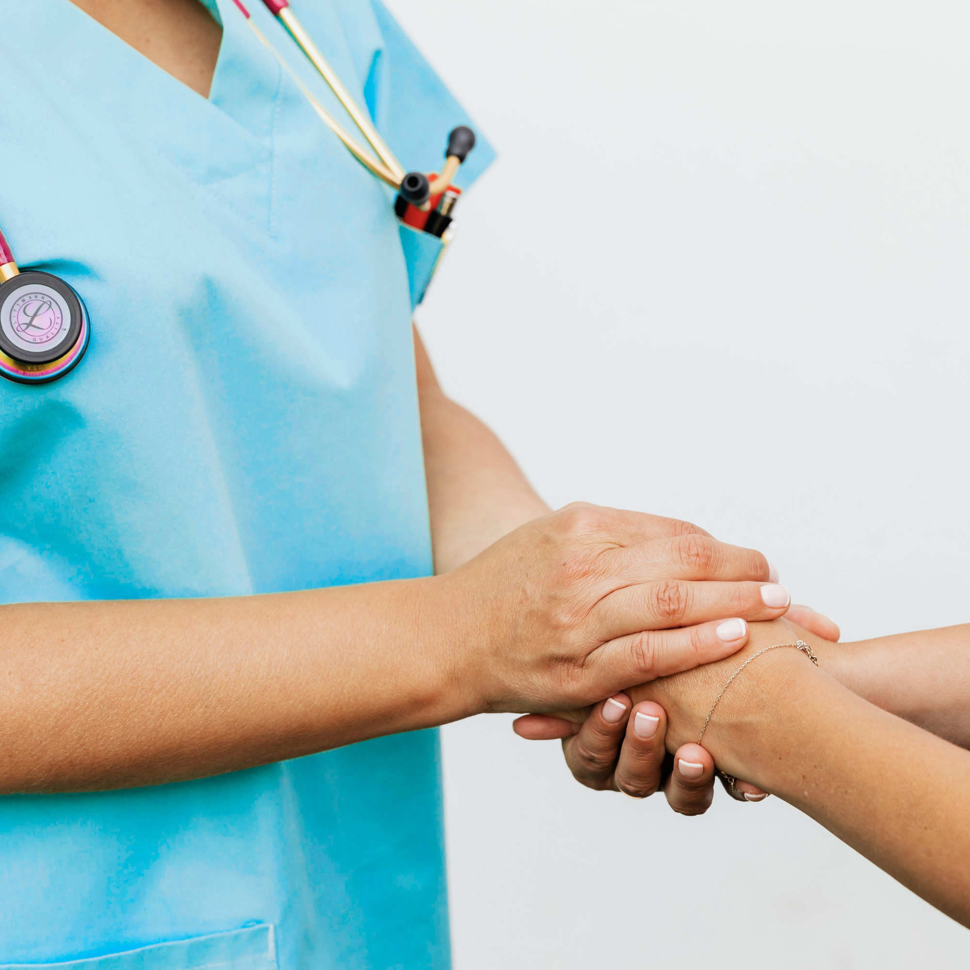 A healthcare professional holding a patient's hand, reassuring the patient that everything will be ok.