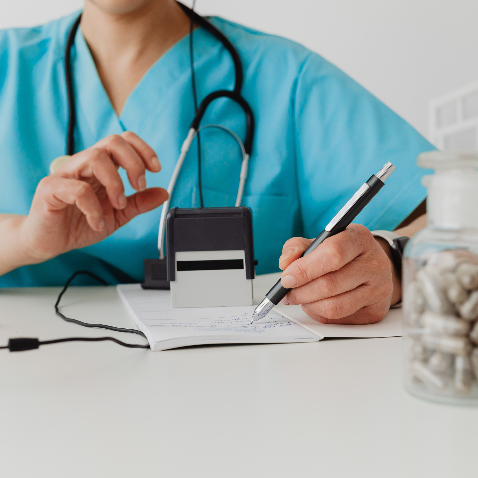 A medical professional is writing on a note with a pen, on a white table, with medication nearby, helping a patient.