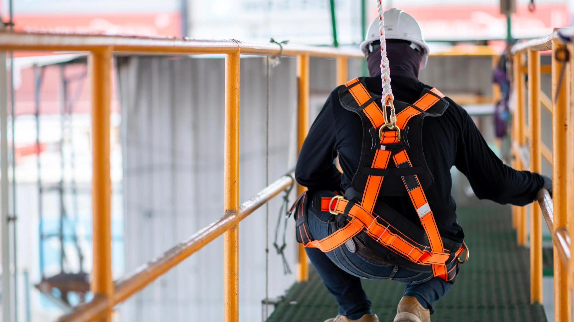 Worker in safety harness and helmet on construction scaffolding