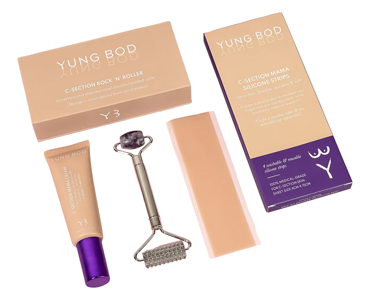 Beauty tools including a jade roller with a gemstone at the end, a silicone scrub pad, and cream packaging from Yung BOB that say 'C-SECTION ROCK 'N' ROLLER,' 'C-SECTION MAMA SILICONE STRIPS,' and other labels, all arranged on a dark background.
