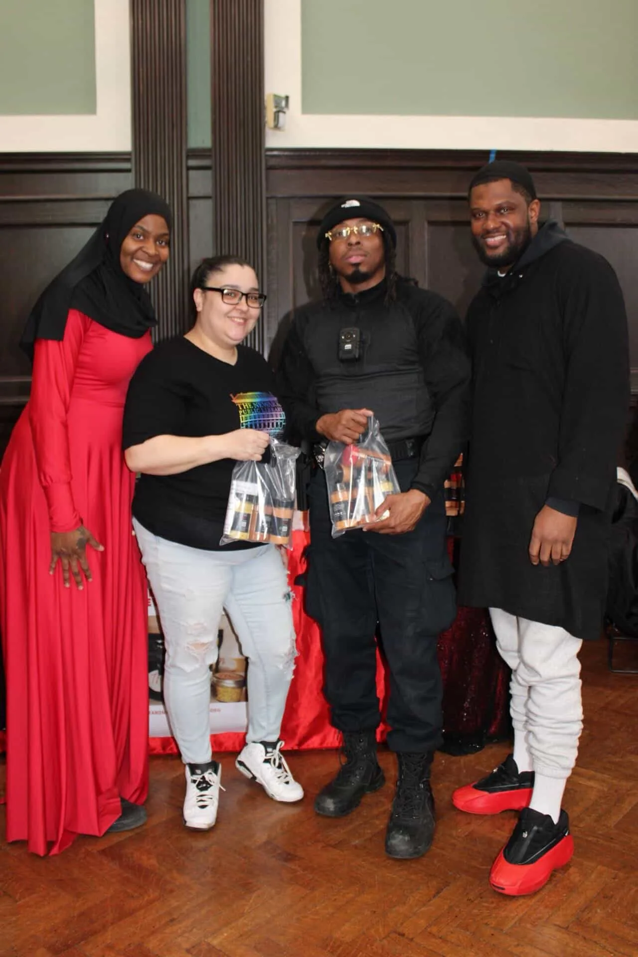 Four people standing together indoors, holding small gift bags, smiling at the camera.