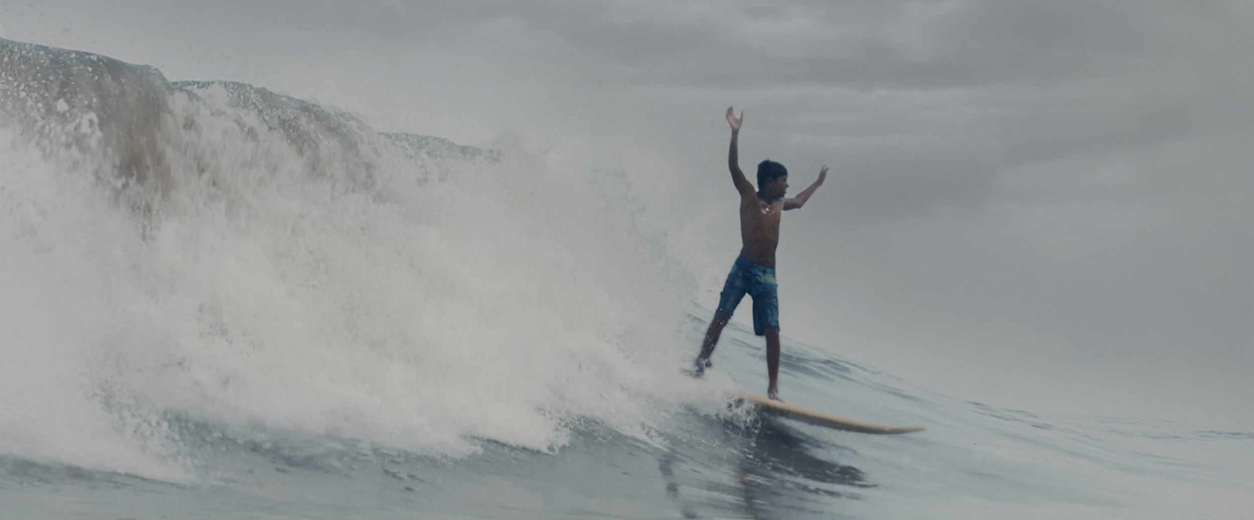 Young man surfing on a wave with arms raised