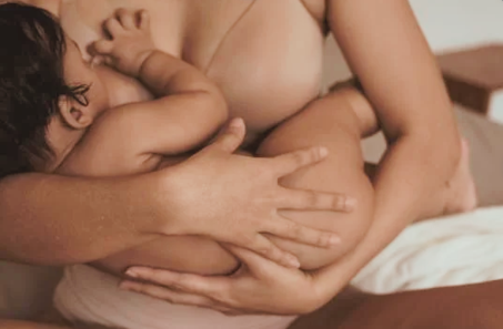 A person breastfeeding a baby in a cozy setting.