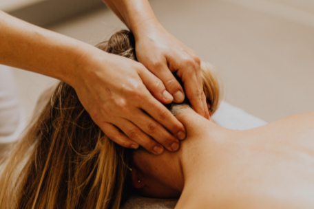 Person receiving a massage with hands applying pressure to the neck and shoulders.