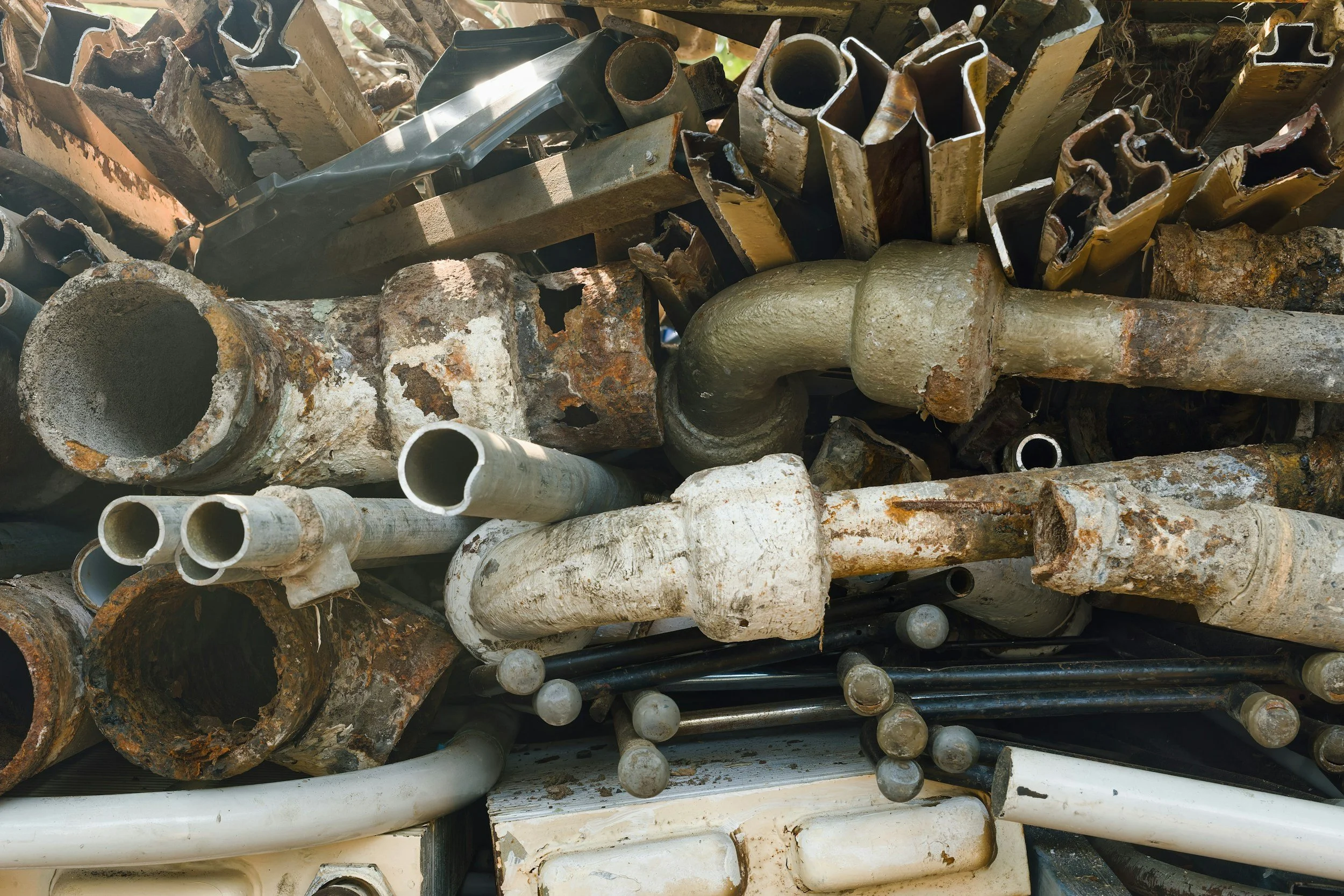 Pile of rusted and used metal pipes and rods in various sizes and shapes.