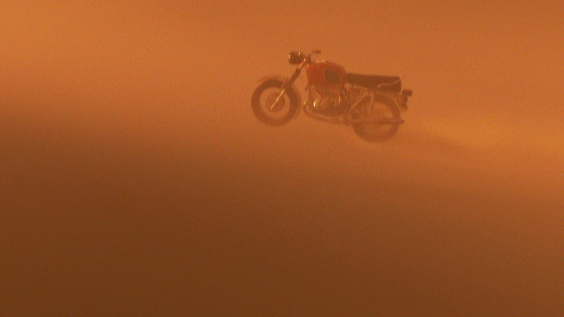 Motorcycle floating inside a dust storm with an orange hue.