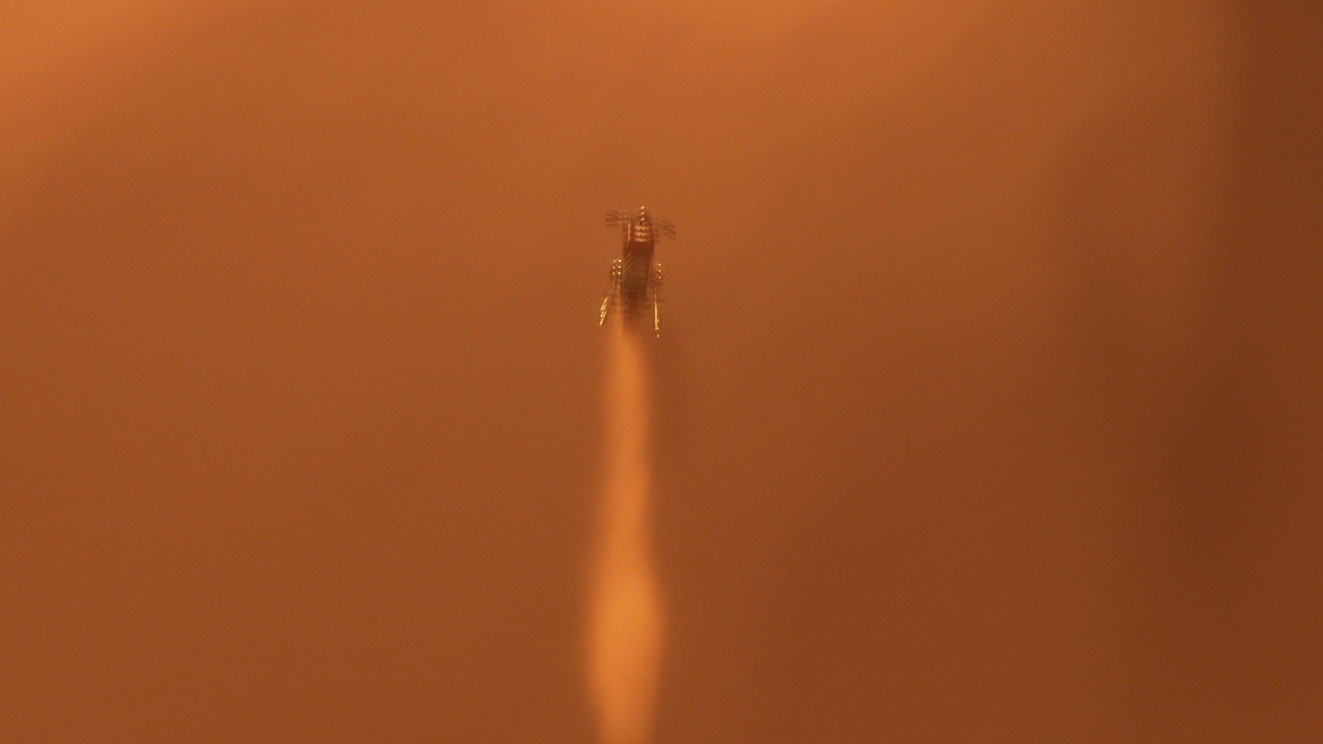 A rocket launching with bright exhaust flames against a brownish sky.