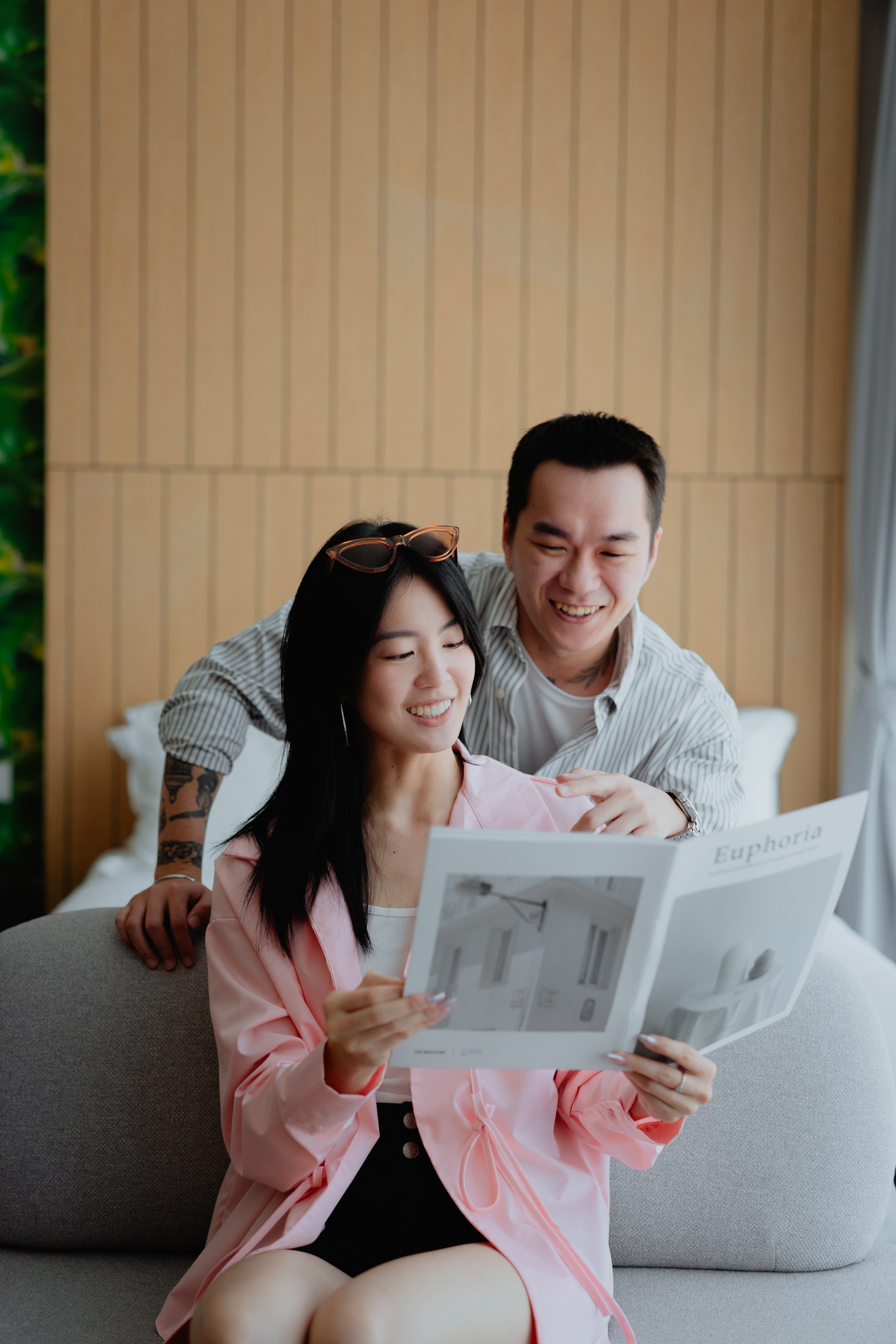 A man and woman looking at a home decor catalog in a cozy living room.