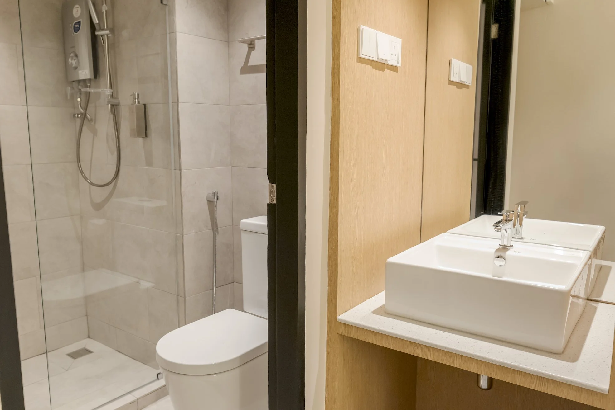 Bathroom with a walk-in shower, toilet, and a vanity with a square white sink and faucet.