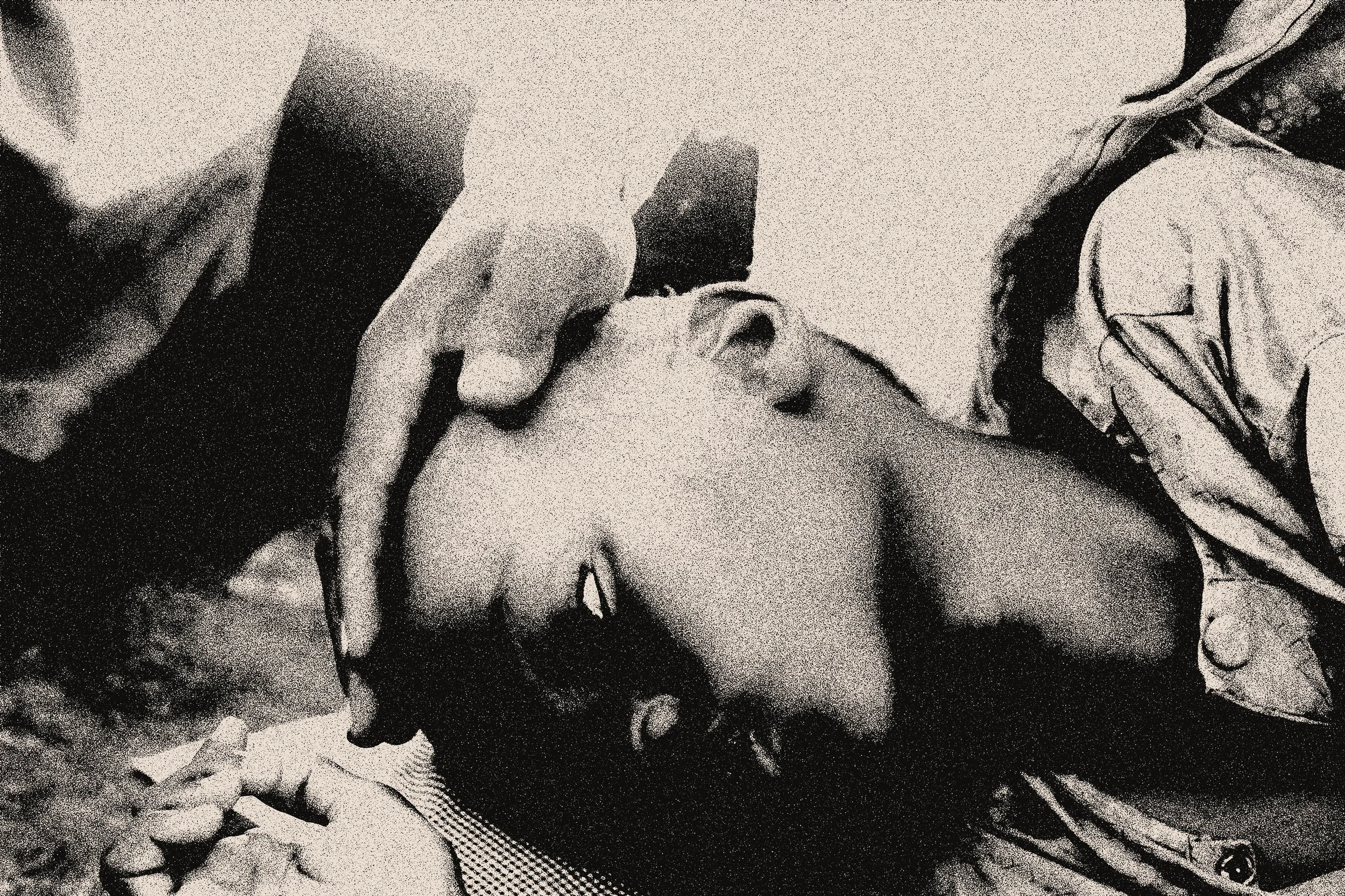 A person lying down with eyes closed, receiving a gentle forehead massage from another person, in black and white.