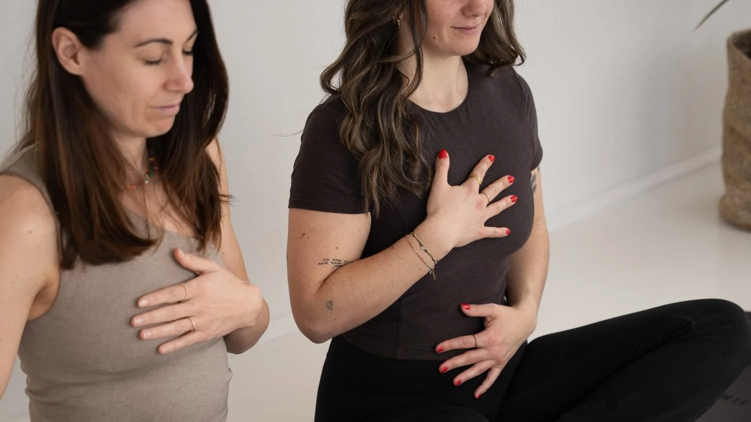 Zwei Frauen mit einer Hand auf der Brust bei einer geführten Atemübung