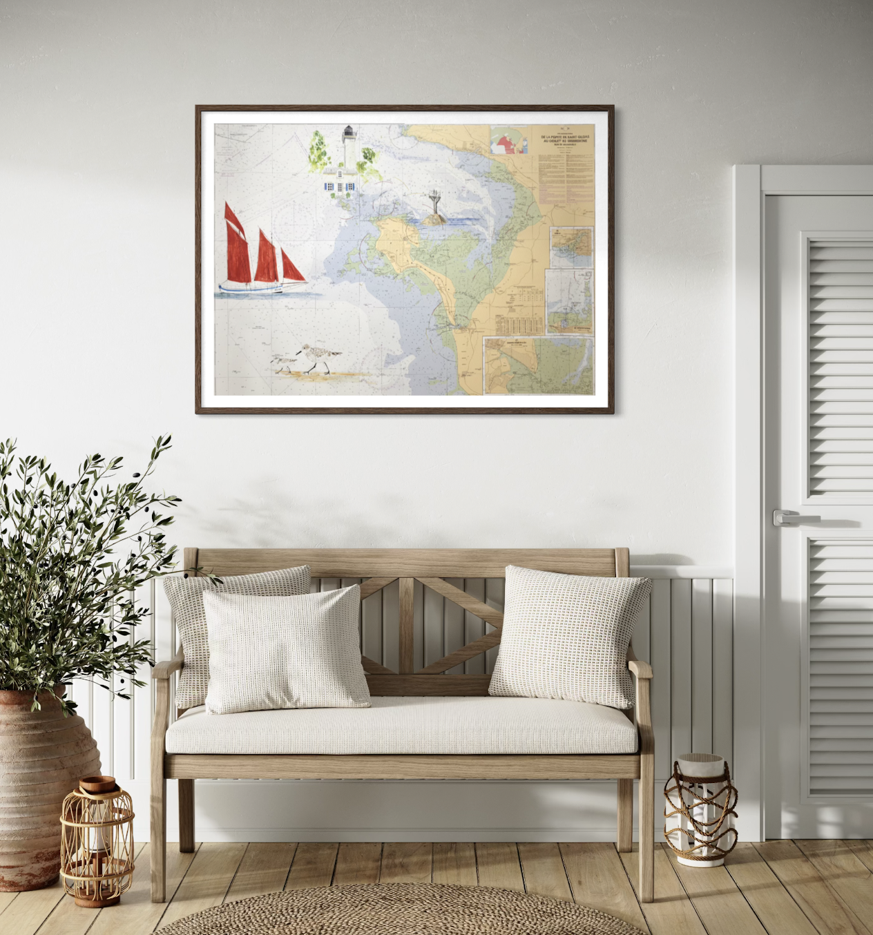Un tableau représentant une carte de la baie de Saint-Quay, avec des illustrations de voiliers, de phares, et d'oiseaux, accroché au mur au-dessus d'un banc en bois avec deux coussins, dans une pièce lumineuse et décorée avec une grande plante en pot