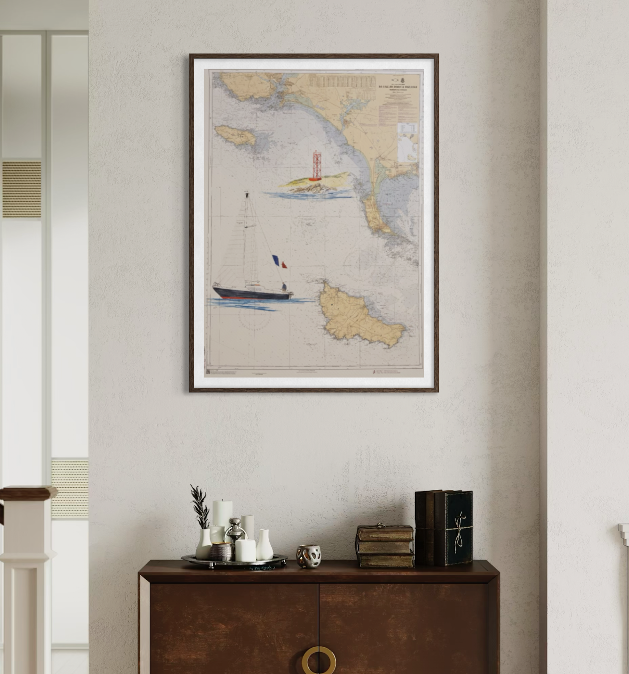 Carte maritime ancienne encadrée sur un mur blanc, avec un bateau à voile et des îles