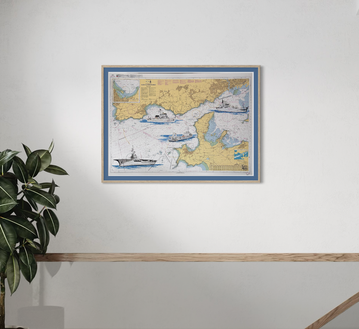 Carte maritime avec illustrations de navires dans la mer, encadrée et accrochée au mur, à côté d'une plante verte.