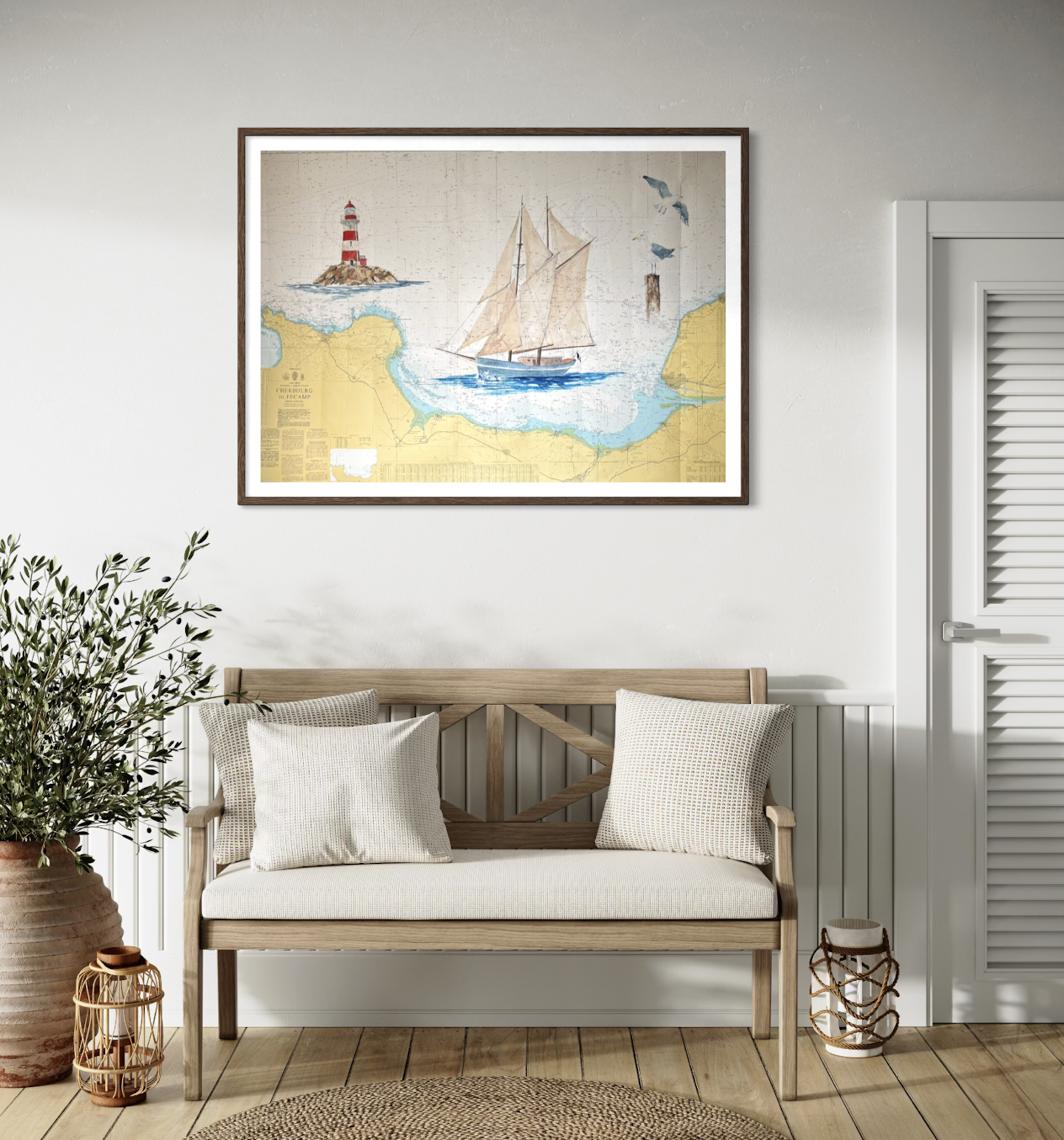 Tableau d'une carte maritime avec un bateau à voile, une lanterne maritime, un phare et des oiseaux, accroché au mur d'une pièce décorée d'un canapé en bois avec des coussins et une plante en pot.