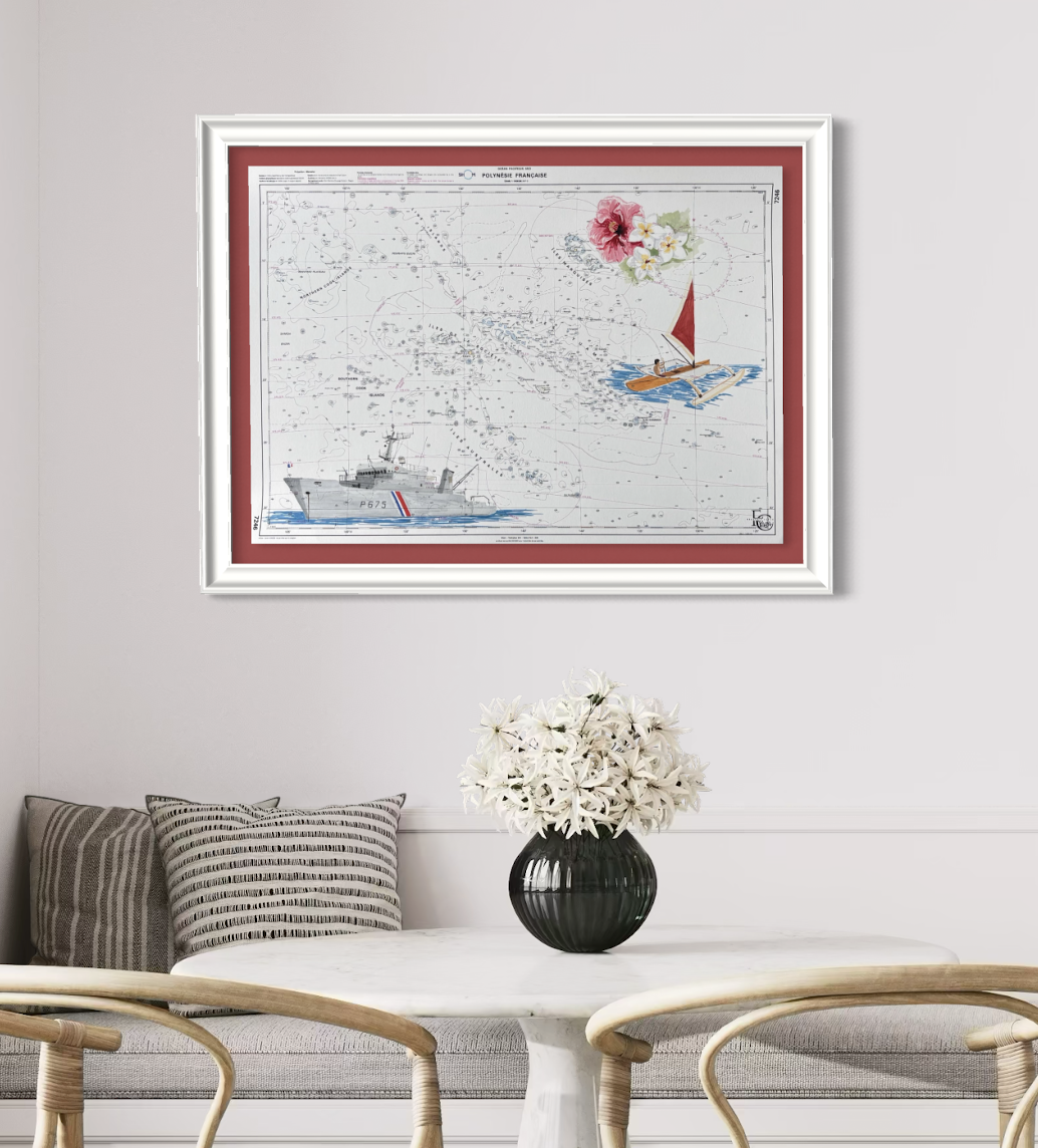 Photo d'une décoration intérieure avec un tableau représentant une carte de Polynésie française, ornée de dessins d'un bateau à voile et d'un navire. Le tableau est encadré dans une moulure blanche avec un fond rouge. En dessous, il y a une table bla
