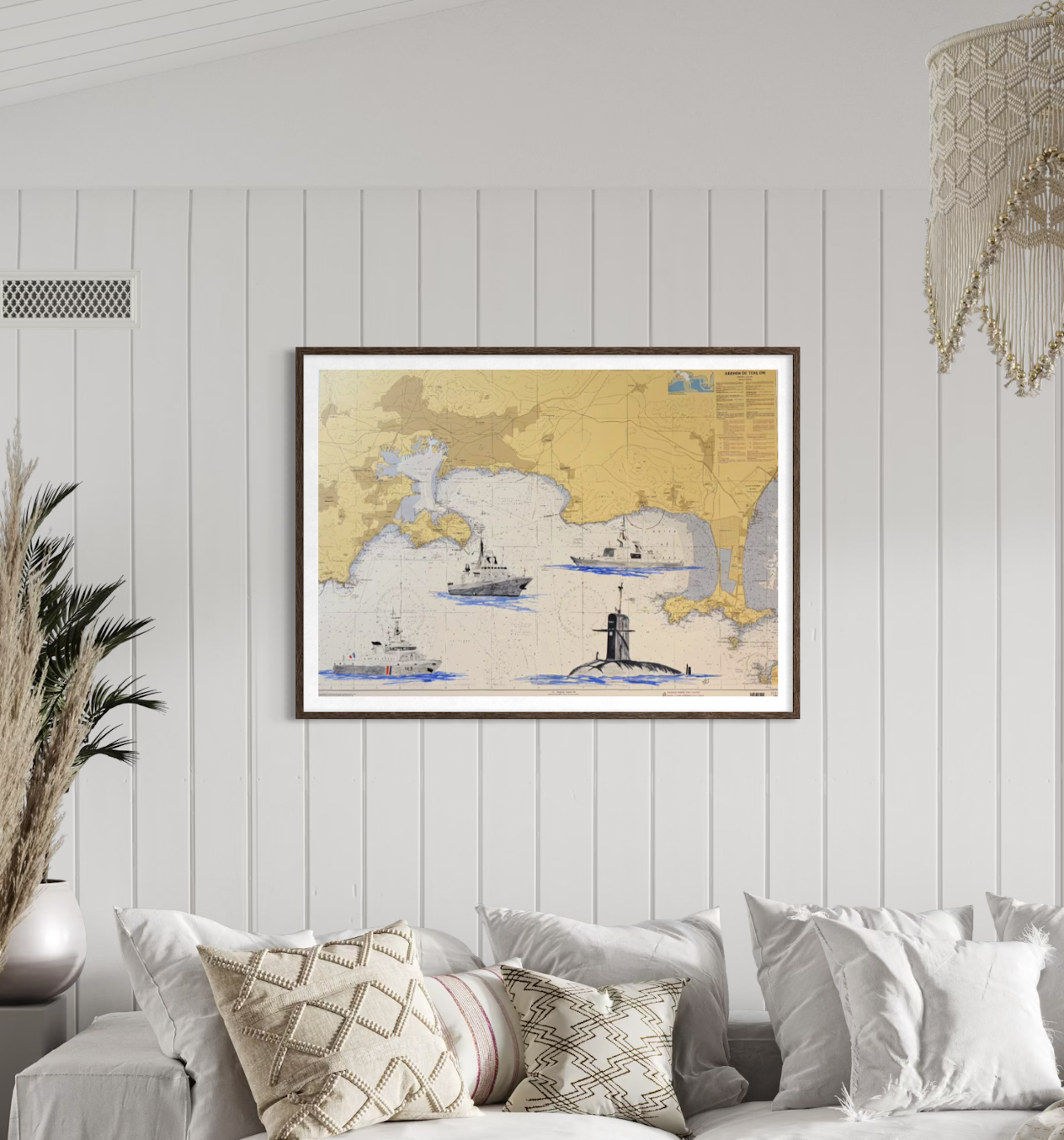 Une affiche illustrée de bateaux et d'une tour située sur une carte géographique dans un salon avec un mur en bois blanc, une plante dans un vase blanc et des coussins sur un canapé beige.