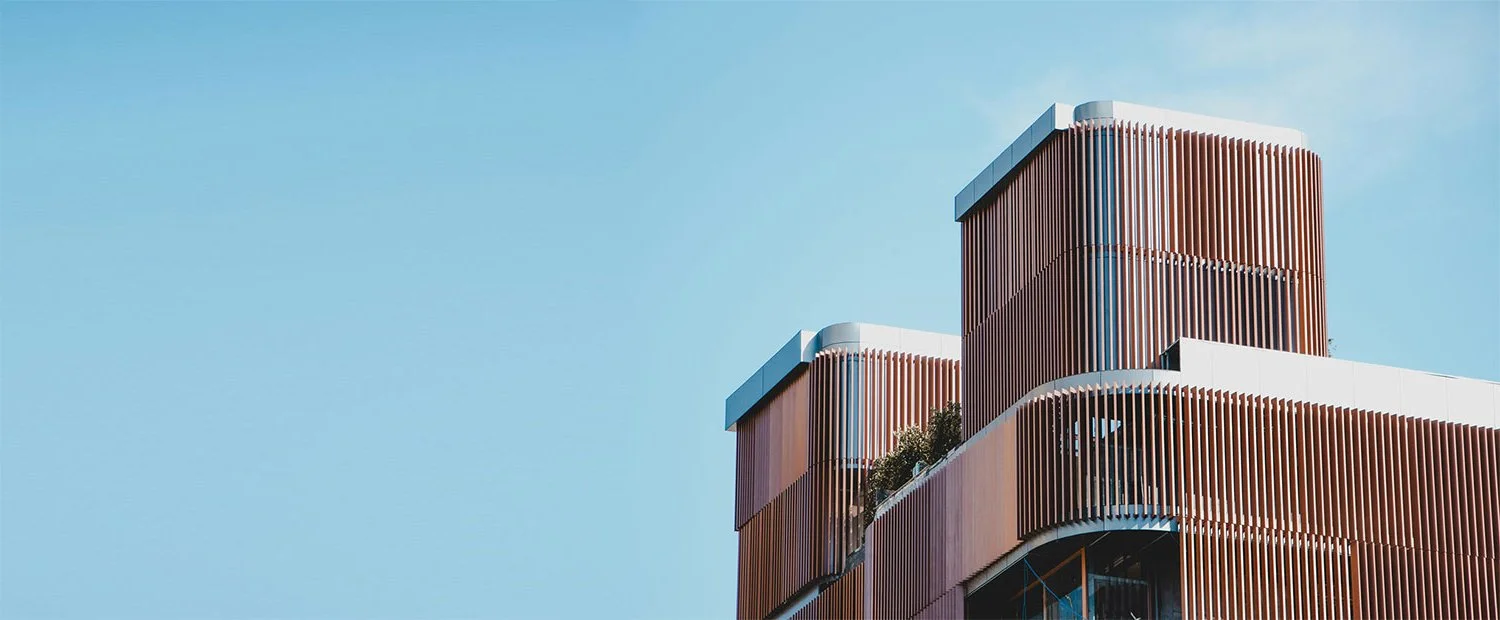 Modern building with vertical wooden slats and glass windows against a clear blue sky.