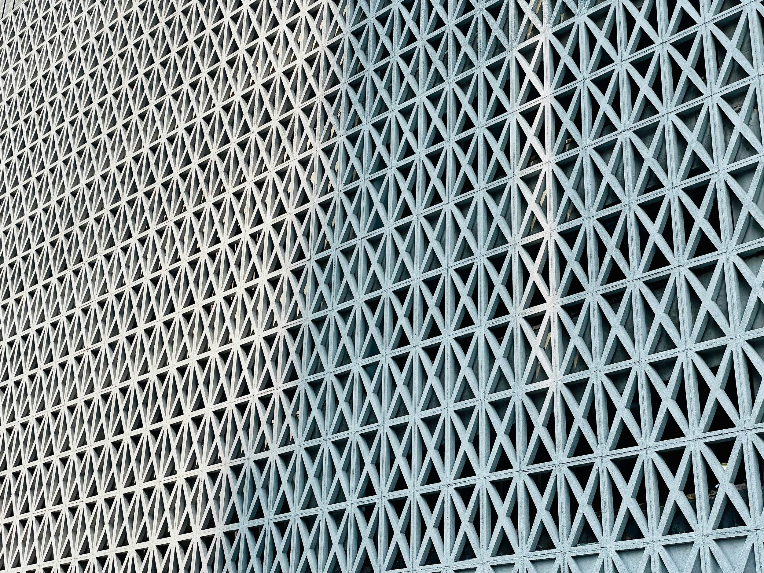 Close-up of a modern architectural building facade with a lattice pattern of repeating diamond-shaped openings.