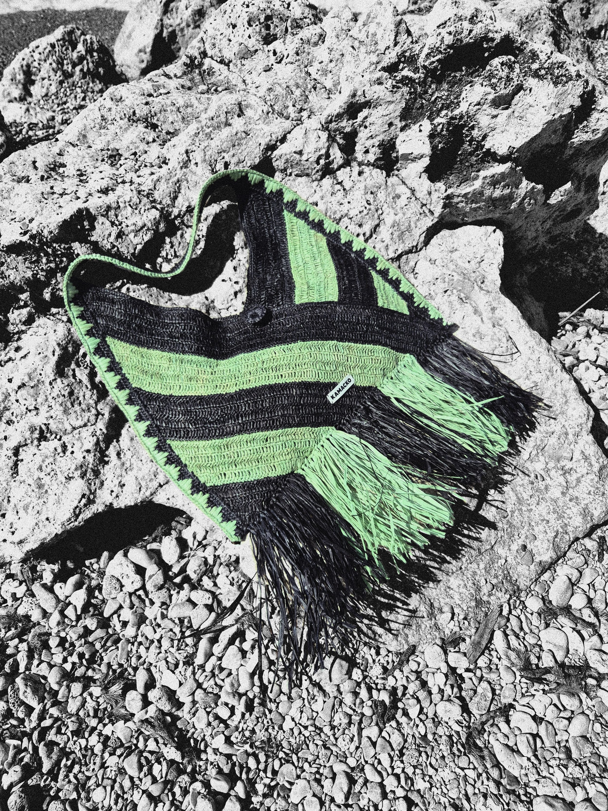Packshot crochet bag in raffia Le Agulla from the label 'KAMACKO' in black and green stripes and fringes.