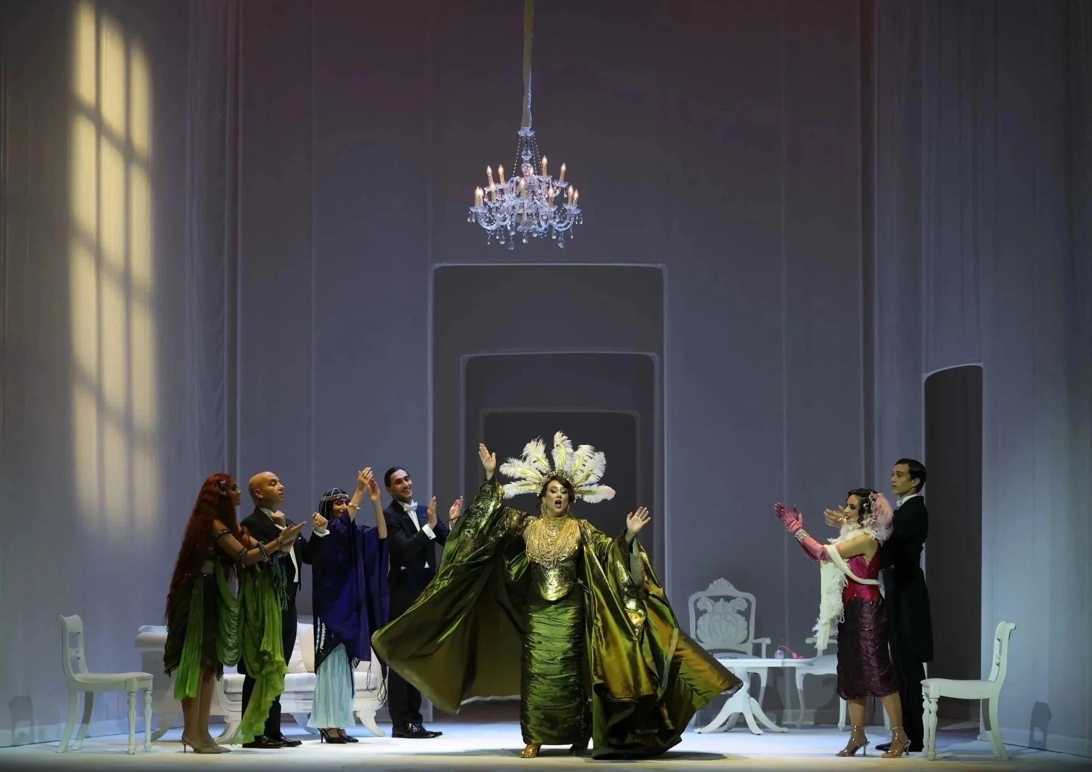 Scene from Gluck’s Il Parnaso confuso at the Valletta Baroque Festival, directed by Brett Nicholas Brown, featuring a central performer in a green costume within a stylised salon setting