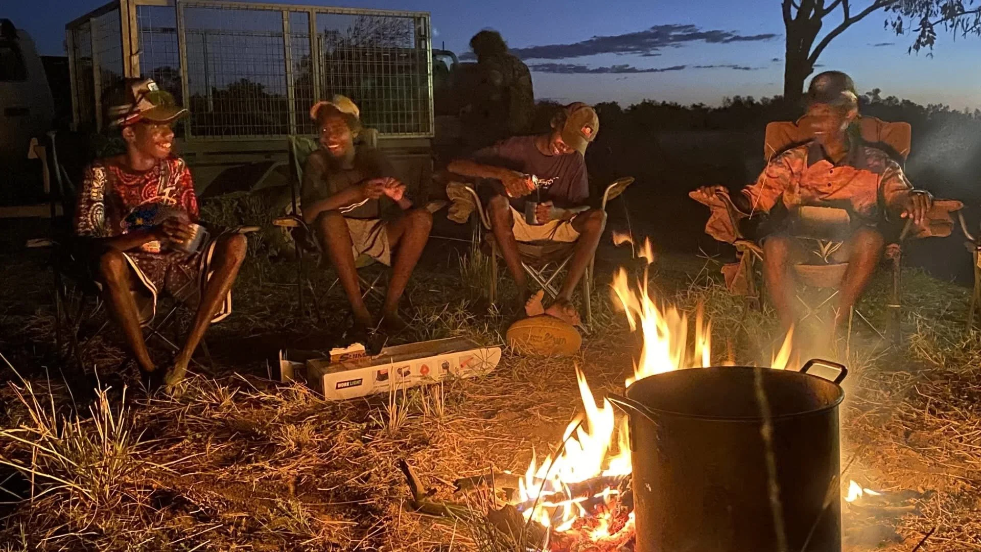 Men in chairs around campfire