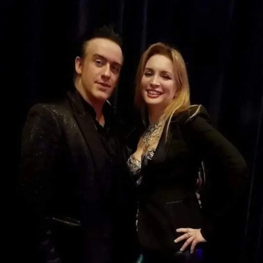 Un homme et une femme souriant, posant pour une photo dans un cadre sombre.