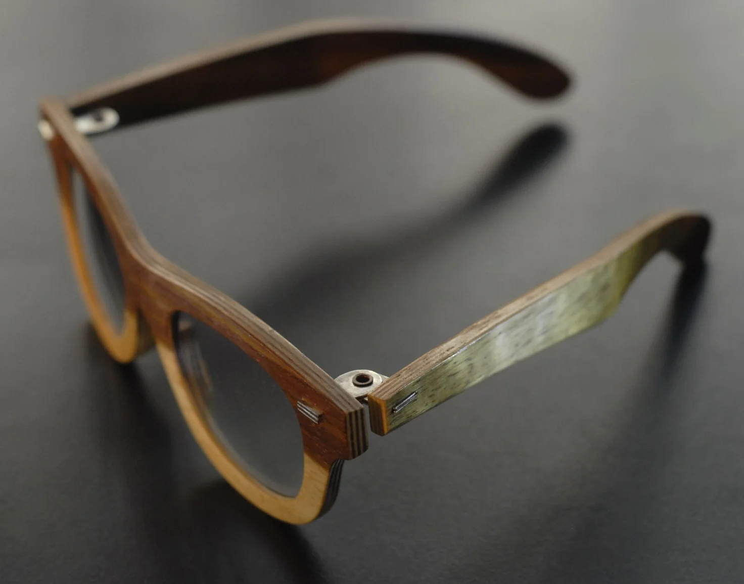 Close-up of wooden sunglasses on black surface.