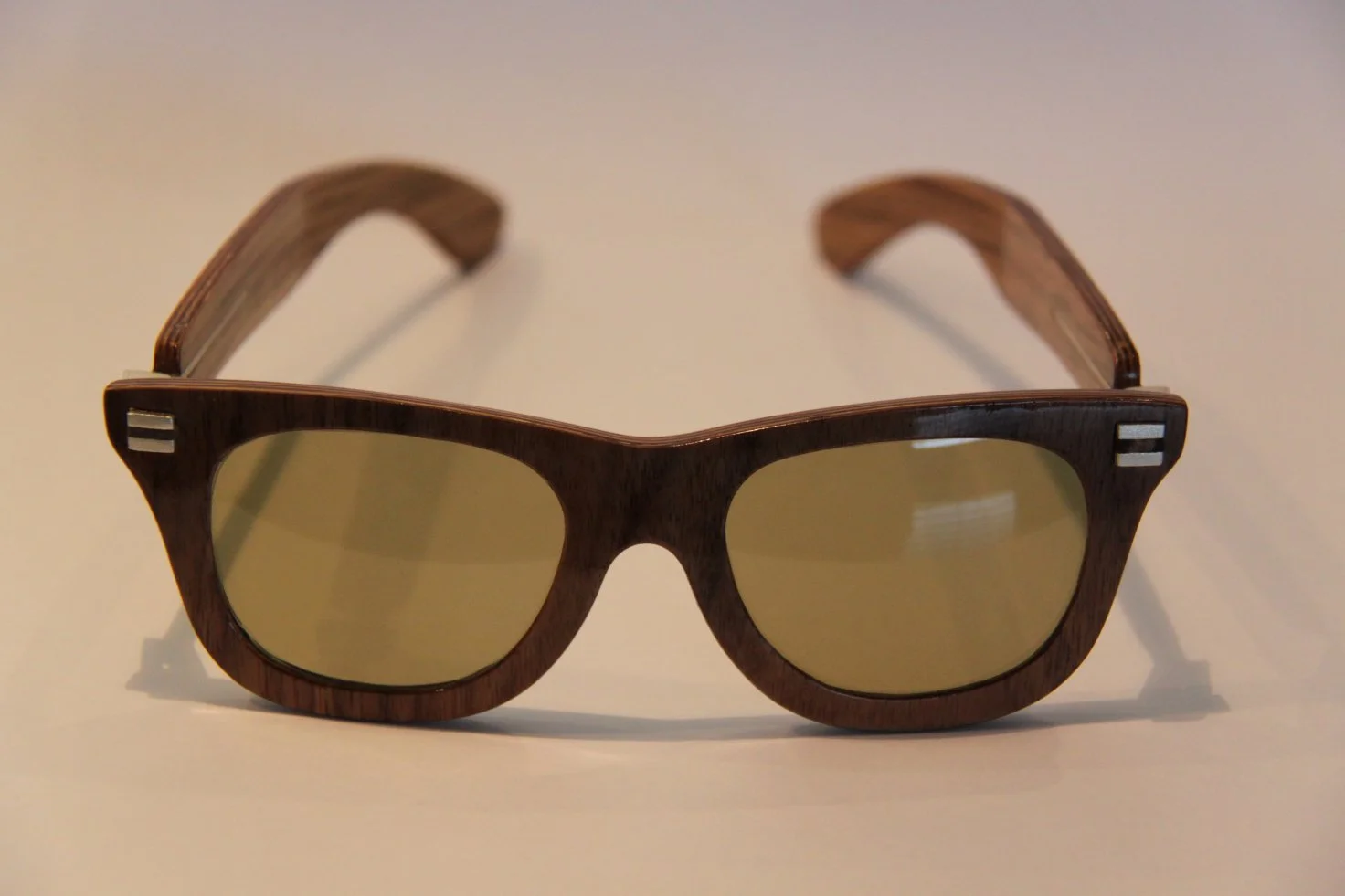 Wooden sunglasses with yellow-tinted lenses on a white surface.