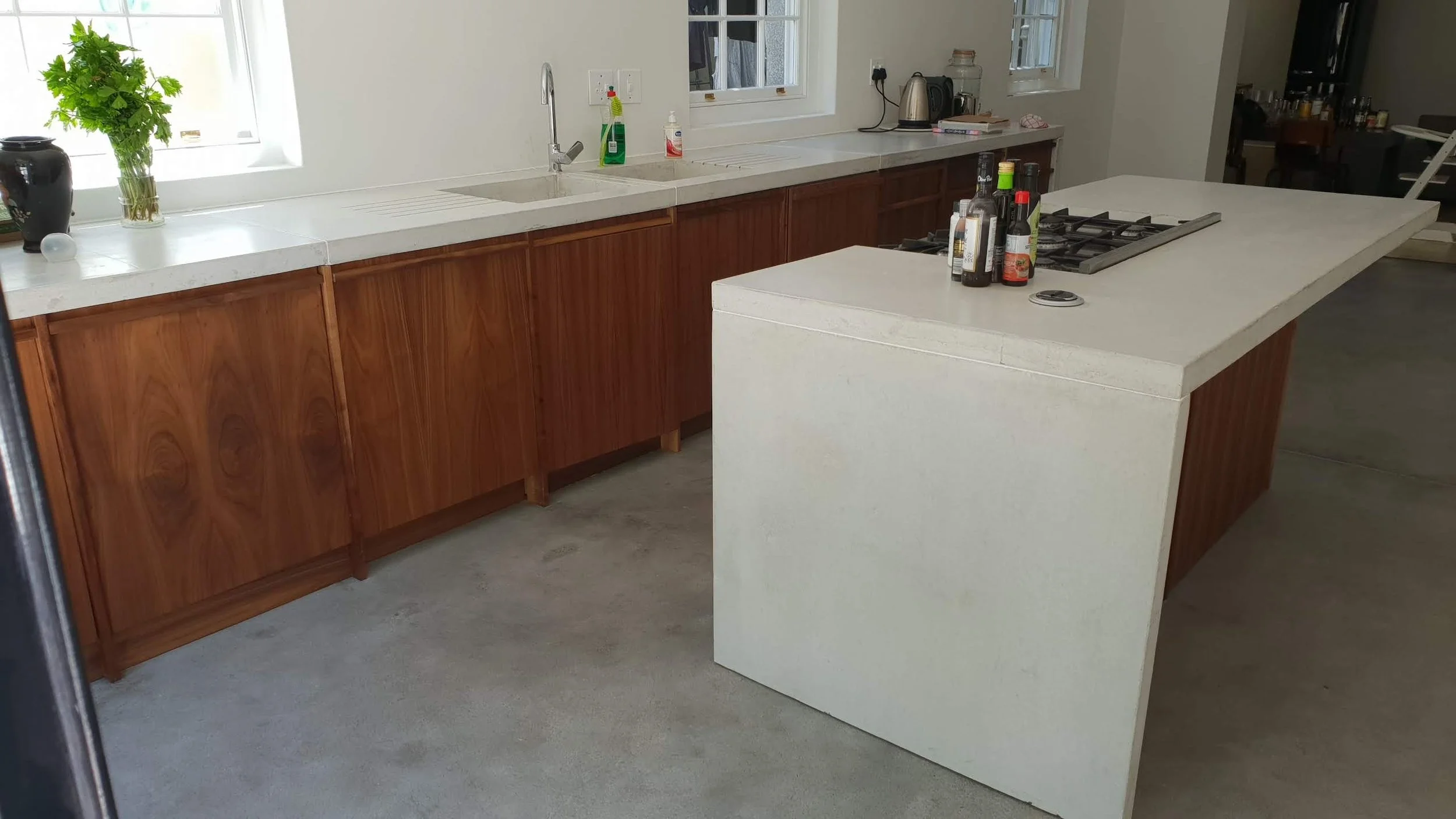 A walnut timber kitchen, etched off by custom-designed and hand-cast white concrete worktops.