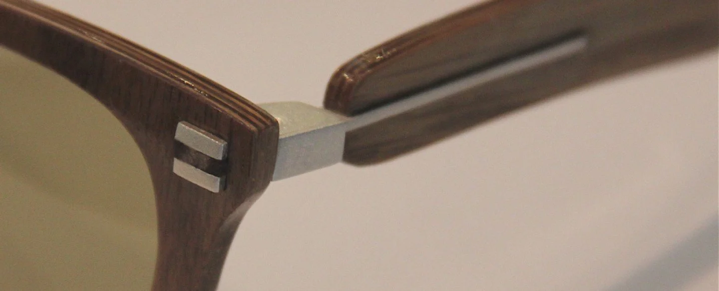 Close-up of the arm and hinge of a wooden chair with metal joints.