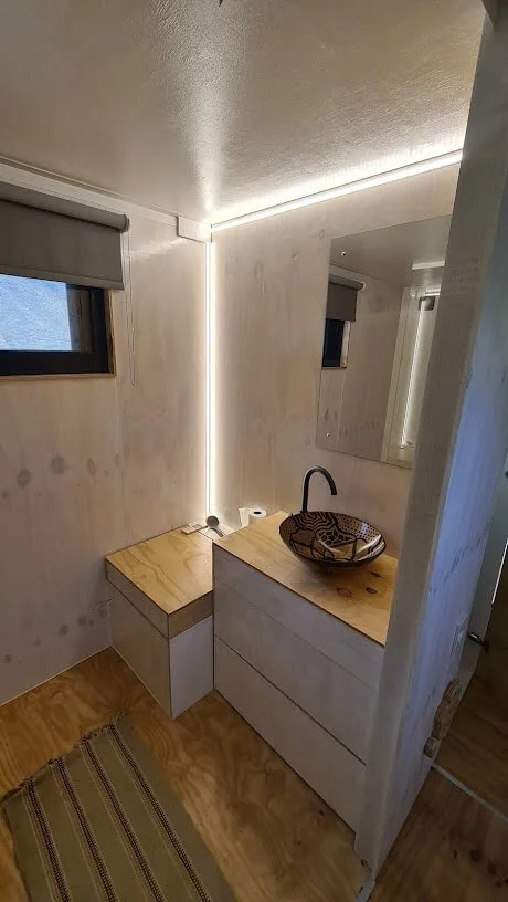 More cupboard space for clothes in the passage which serves as a dressing room adjacent to the tiny house bathroom.