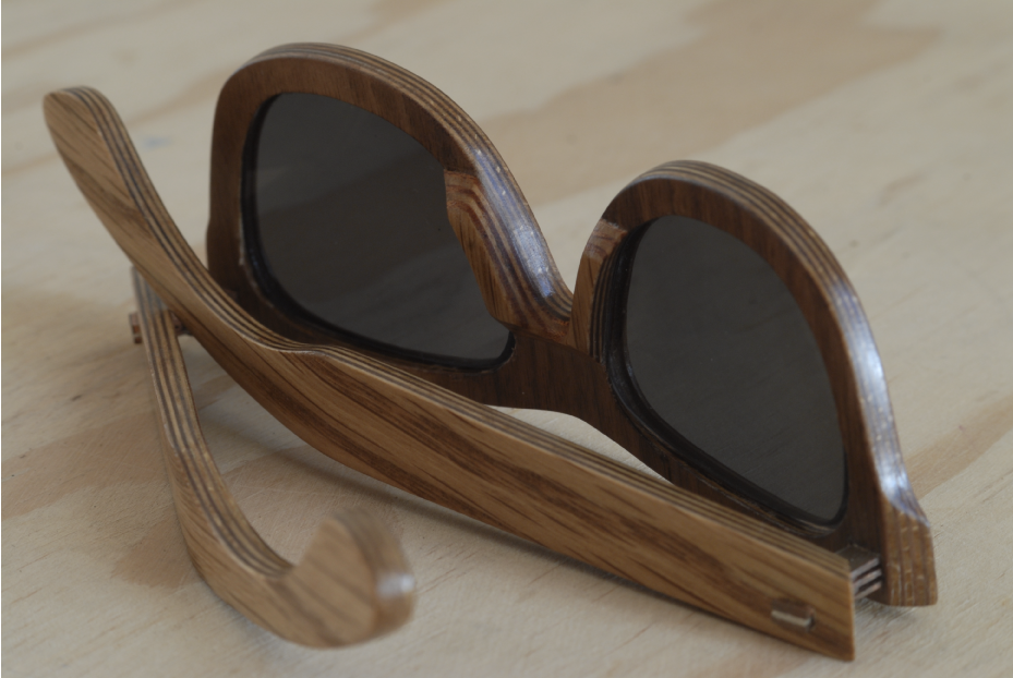 Wooden sunglasses with dark lenses resting on a light wooden surface.