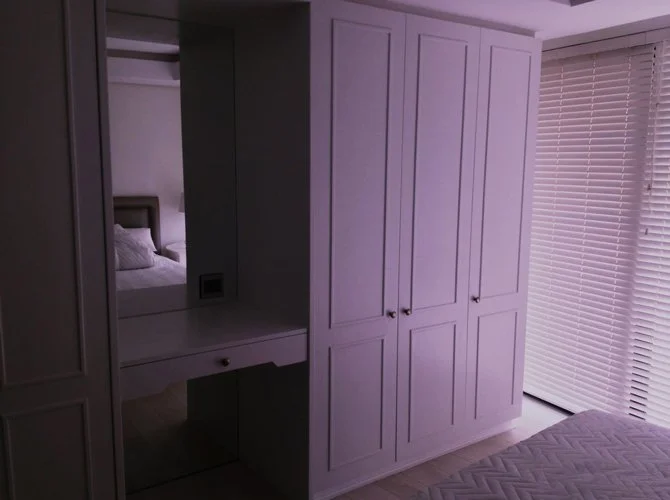 A bedroom with a large built-in closet, a mirror, and a window with closed blinds.