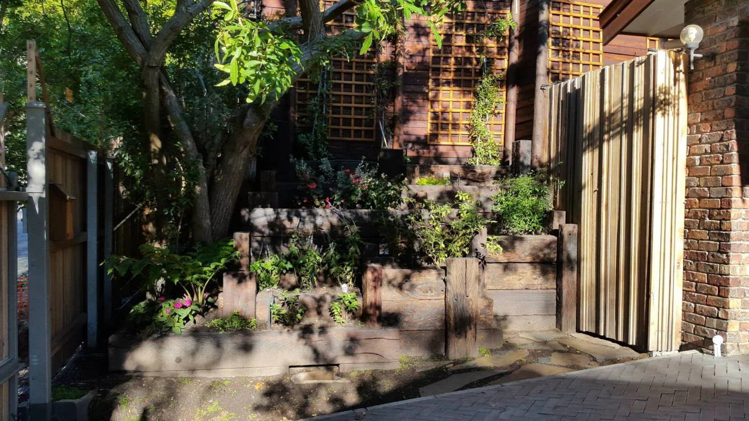 Solid railway sleepers arranged to form a terraced planter. Terraces of solid sleepers make for easy access to plants at the top.
